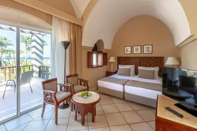 a hotel room with a bed and a television and a balcony at Iberotel Makadi Beach in Hurghada