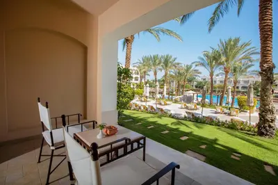 a patio with a table and chairs and palm trees at JAZ Makadi Star & Spa in Hurghada