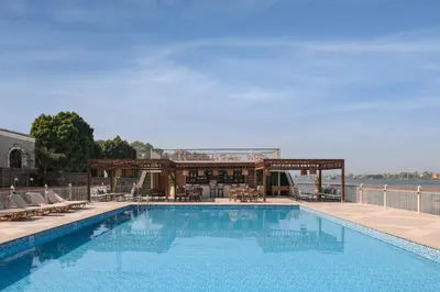 a large swimming pool with chairs and a building at Iberotel Luxor in Luxor