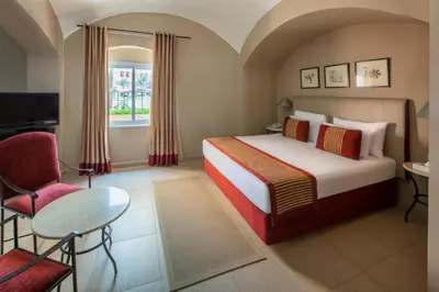 a hotel room with a bed and a chair at JAZ Makadi Oasis Resort in Hurghada