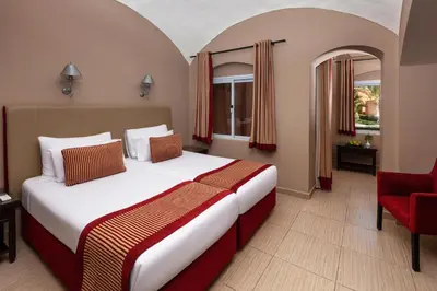 a hotel room with a bed and a red chair at JAZ Makadi Oasis Resort in Hurghada