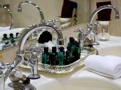 a bathroom sink with a tray of green glass bottles at Sofitel Winter Palace Luxor in Luxor