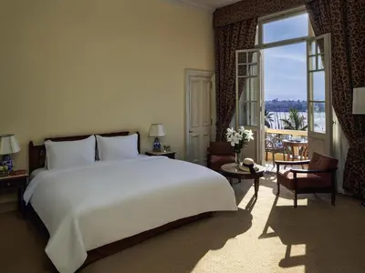 a bedroom with a large white bed and a large window at Sofitel Winter Palace Luxor in Luxor