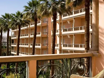a balcony with palm trees in front of a building at Pavillon Winter Luxor in Luxor