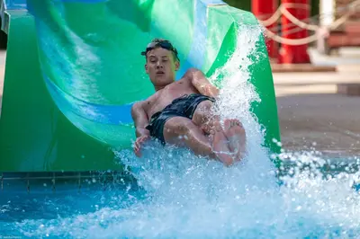 a young man riding a slide in a water park at Casa Mare Resort - ex, Royal Tulip Beach Resort in Port Ghalib