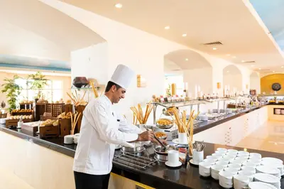 a chef preparing food in a restaurant kitchen at Three Corners Ocean View El Gouna - Adults Only in Hurghada