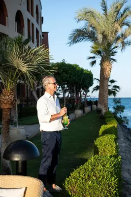 a man standing in the grass near a palm tree at Three Corners Ocean View El Gouna - Adults Only in Hurghada