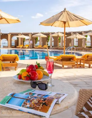 a table with a plate of fruit and a glass of wine at Three Corners Ocean View El Gouna - Adults Only in Hurghada