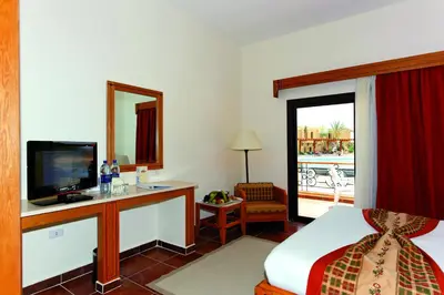 a hotel room with a bed and a desk with a television at Three Corners Fayrouz Plaza Beach Resort in Port Ghalib