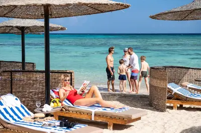 a woman in a red bikini sitting on a beach at Three Corners Fayrouz Plaza Beach Resort in Port Ghalib