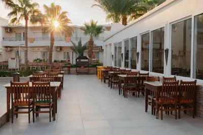 a restaurant with tables and chairs and palm trees at Empire Beach Aqua Park in Hurghada