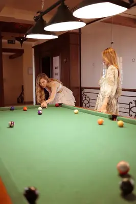 two women are playing pool on a pool table at The Cascades Golf Resort, Spa & Thalasso in Hurghada