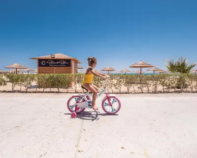 a young girl riding a bike on the beach at The Cascades Golf Resort, Spa & Thalasso in Hurghada