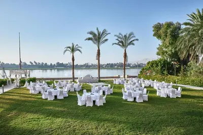 a group of white chairs on the grass near the water at Steigenberger Resort Achti in Luxor