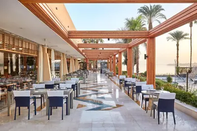 a restaurant with tables and chairs and palm trees at Steigenberger Resort Achti in Luxor