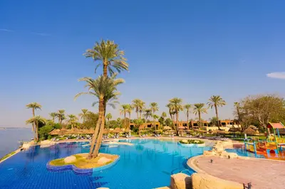 a large swimming pool with palm trees and water at Jolie Ville Hotel & Spa Kings Island Luxor in Luxor