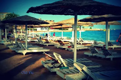 a group of lounge chairs and umbrellas on a beach at Elaria Hotel Hurgada in Hurghada