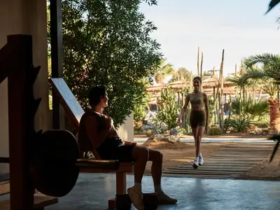 a man sitting on a bench and a woman walking at Cook’s Club El Gouna (Adults Only) in Hurghada