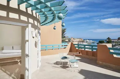 a balcony with a bed and chairs and a view of the ocean at Captain's Inn Hotel in Hurghada