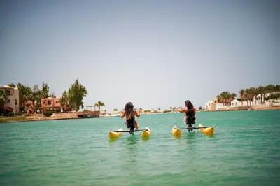 two girls are riding on kayaks in the water at Captain's Inn Hotel in Hurghada