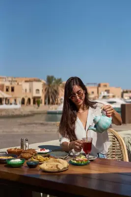 a woman sitting at a table with a drink at Ali Pasha Hotel in Hurghada