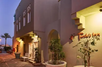 a building with potted plants in front of it at Turtle's Inn Hotel in Hurghada