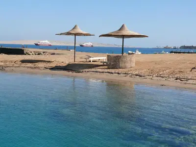 a beach with umbrellas on the sand and water at Mini-Studio With Free Private Beach in Hurghada