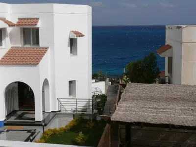 a white building with the ocean in the background at Mini-Studio With Free Private Beach in Hurghada