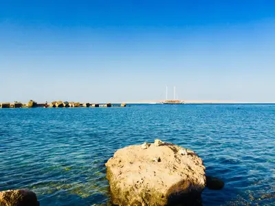 a rock in the water with a ship in the distance at Diamond Arabia Orange in Hurghada