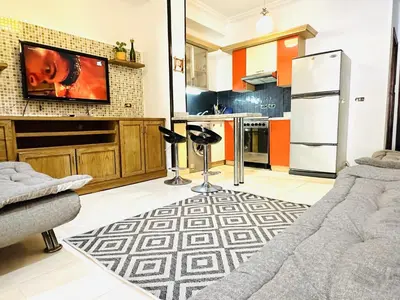 a kitchen with a couch and a tv on a wall at Diamond Arabia Orange in Hurghada