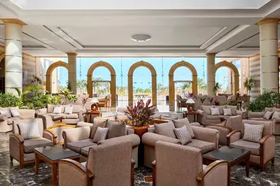 a large lobby with chairs and tables and windows at JAZ Grand Marsa in Coraya Bay