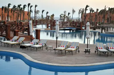 a pool at a resort with chairs and umbrellas at JAZ Grand Marsa in Coraya Bay