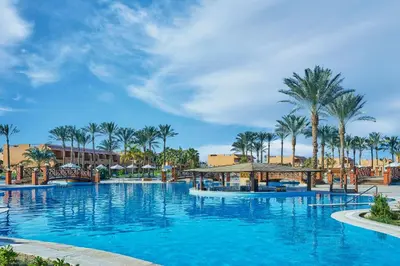 a large swimming pool with palm trees in the background at JAZ Grand Marsa in Coraya Bay