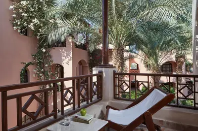 a balcony with a chair and a table and palm trees at Hotel Sultan Bey Resort in Hurghada