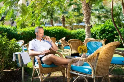 a man sitting in a chair talking on a cell phone at Three Corners Sunny Beach Resort in Hurghada