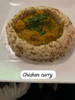 a plate of food with a dish of chicken curry at Gaddis Hotel, Suites and Apartments in Luxor