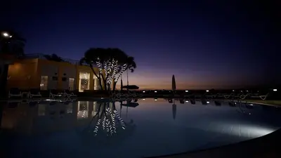 a swimming pool at night with chairs and a building at Lotus Luxor Hotel in Luxor