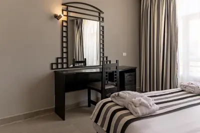 a bedroom with a mirror and a desk and a bed at Sunny Days Mirette Family Resort in Hurghada