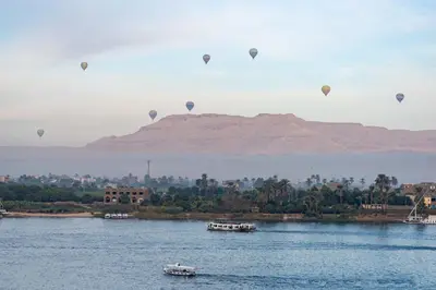 a group of hot air balloons flying over a river at Aracan Eatabe Luxor Hotel in Luxor