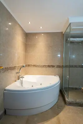 a bathroom with a tub and a glass shower at Aracan Eatabe Luxor Hotel in Luxor