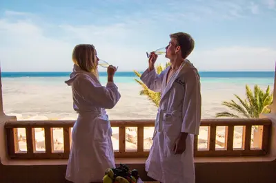 two people drinking from wine glasses on the beach at The Breakers Diving and Surfing Lodge Soma Bay in Hurghada