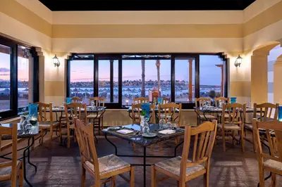 a restaurant with tables and chairs and large windows at JAZ Lamaya Resort in Coraya Bay
