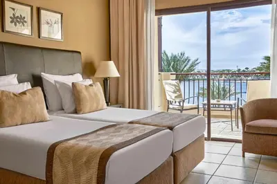 a hotel room with a bed and a balcony at JAZ Lamaya Resort in Coraya Bay