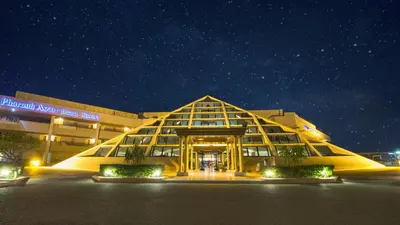 a large building with a glass facade at night at Pharaoh Azur Resort in Hurghada