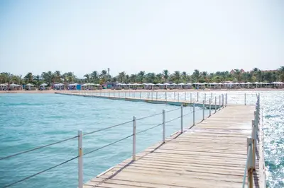 a wooden dock with umbrellas on the water at Pharaoh Azur Resort in Hurghada