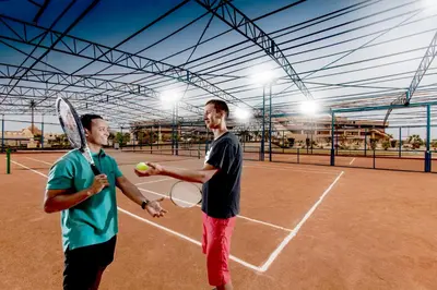 two men playing tennis on a tennis court at Pharaoh Azur Resort in Hurghada