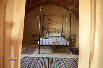 a bedroom with a metal bed in an archway at Qasr El Bagawat Hotel in ‘Ezbet Halfa