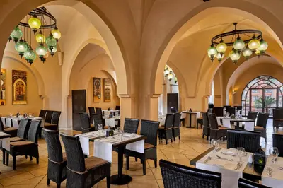 a restaurant with tables and chairs and chandeliers at JAZ Neo Dar El Madina in Coraya Bay