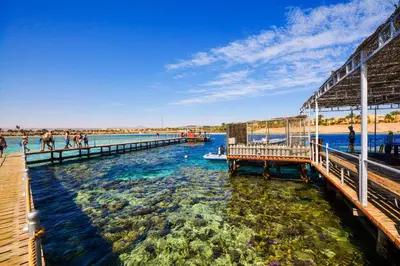 a pier on the water with people on the beach at JAZ Neo Dar El Madina in Coraya Bay