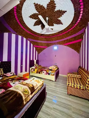 a room with three beds and a large clock on the wall at Fadlos Anay Nubian Guesthouse فضلوس أناي in Aswan